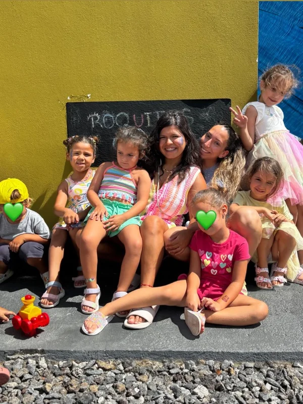 Stephany con un grupo de niños sentados sonriendo en Roquitos Club