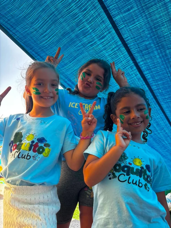 Tres niñas con pintura de cara verde haciendo el signo de la victoria