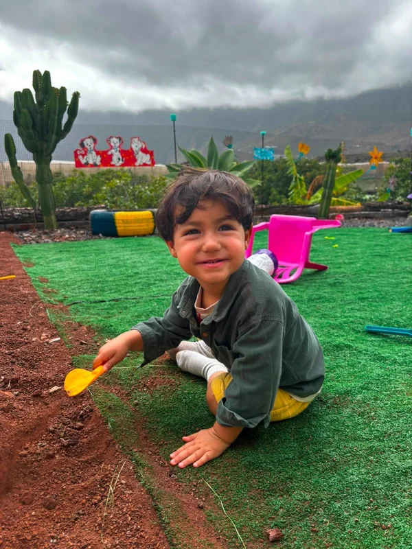 Niño pequeño jugando en la tierra con una pala amarilla de juguete